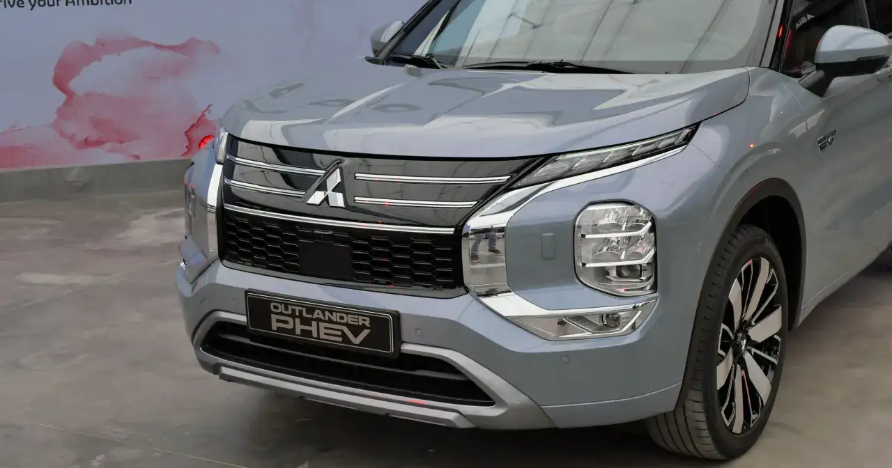 Nowy Mitsubishi Outlander PHEV w kolorze szarym, z charakterystycznym grillem i nowoczesnymi światłami.