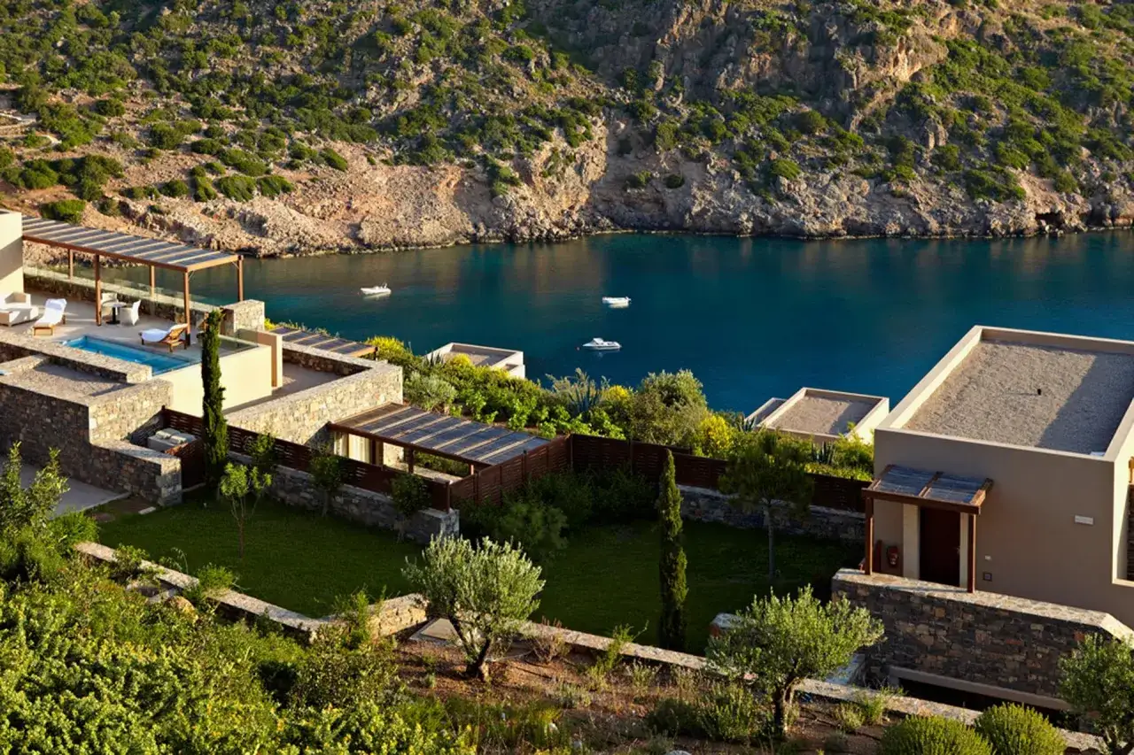 Luxuriöse Villen mit Pool und Blick auf das türkisfarbene Meer in Daios Cove. Boote schaukeln sanft in der Bucht.