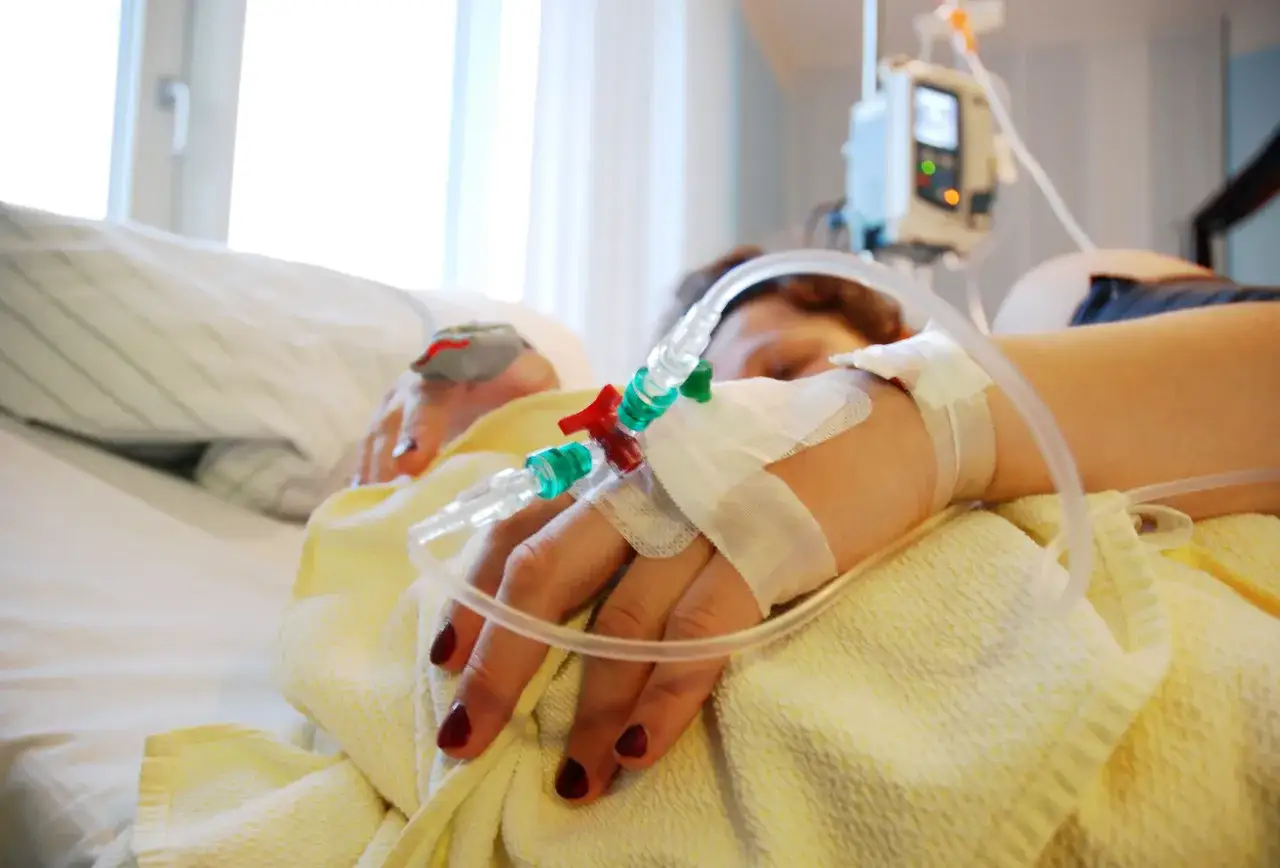 Eine Hand mit Infusionsleitung im Krankenhaus. Die Frage, wie lange dauert eine Einleitung, besch&auml;ftigt viele.