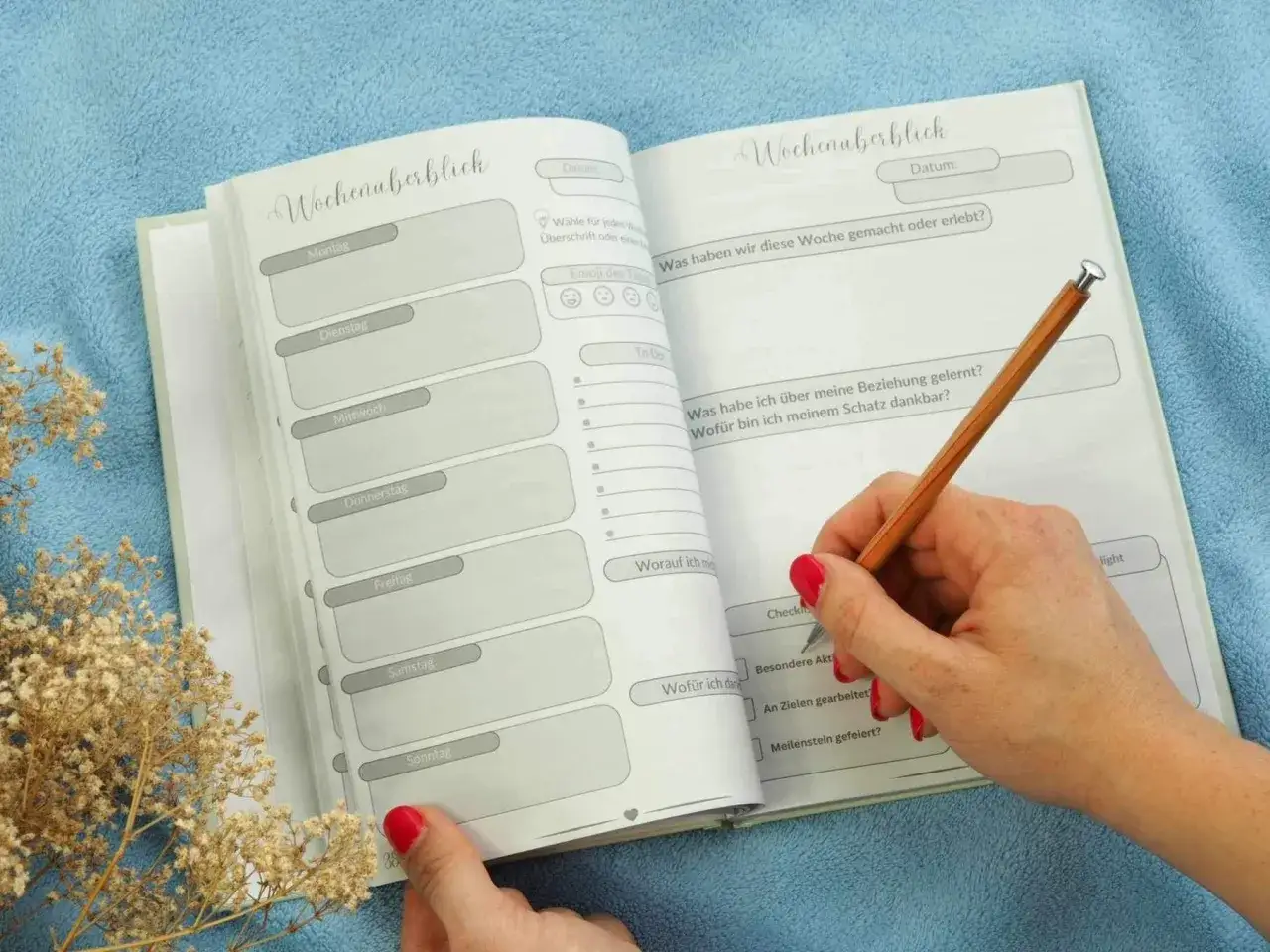 Ein offenes Notizbuch mit Wochen&uuml;bersicht und Fragen zur Selbstreflexion Beziehung. Eine Hand h&auml;lt einen Stift und schreibt.