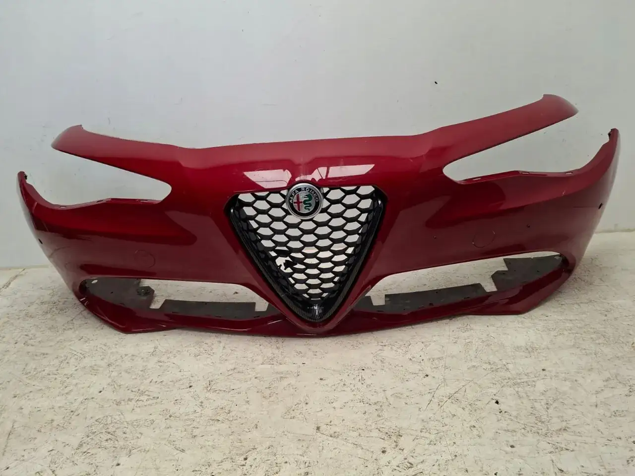 Czerwony zderzak przedni do Alfa Romeo Giulia Q4 z charakterystyczną atrapą chłodnicy w kształcie tarczy.
