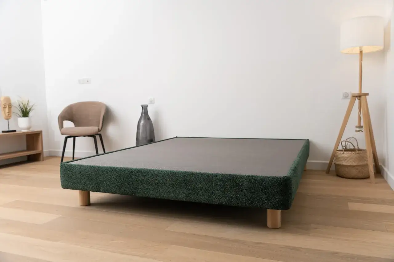 Un sommier tapissier, c'est quoi ? Ce mod&egrave;le vert fonc&eacute;, sur pieds en bois, offre une base solide et esth&eacute;tique pour votre matelas.