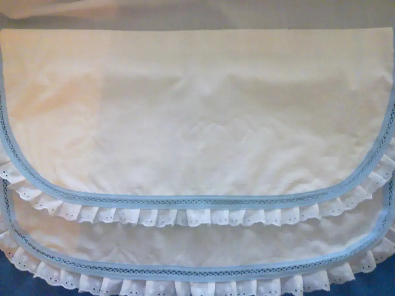 Patrones de sábanas para cochecito de bebé hechas a mano, con delicados volantes y ribete azul.