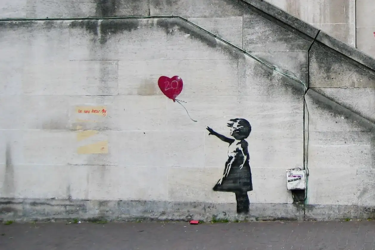 Dziewczynka puszcza czerwony balon w kształcie serca z cyfrą 20. To jedno z najbardziej znanych dzieł Banksy'ego.