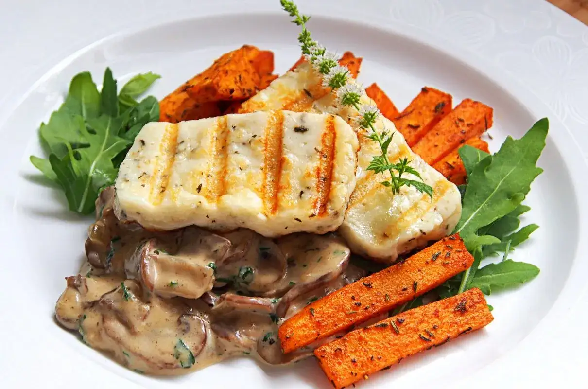 Halloumi z grilla podane z pieczonymi batatami, kremowym sosem grzybowym i rukolą. Pyszne danie pełne smaku.