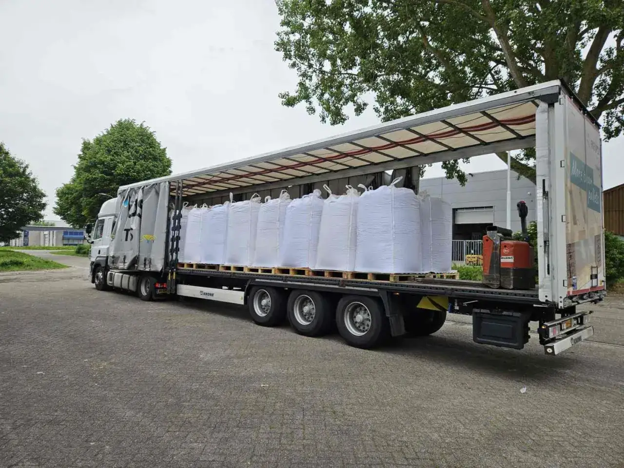 Ein Tautliner-Anh&auml;nger mit vielen wei&szlig;en Big Bags, bereit f&uuml;r den Transport.