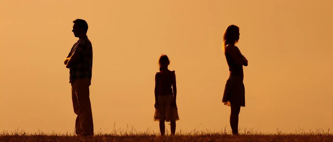 Silhouetten von Eltern, die sich abwenden, w&auml;hrend ein Kind dazwischen steht. Der **Trennungsschmerz Kinder** ist sp&uuml;rbar.