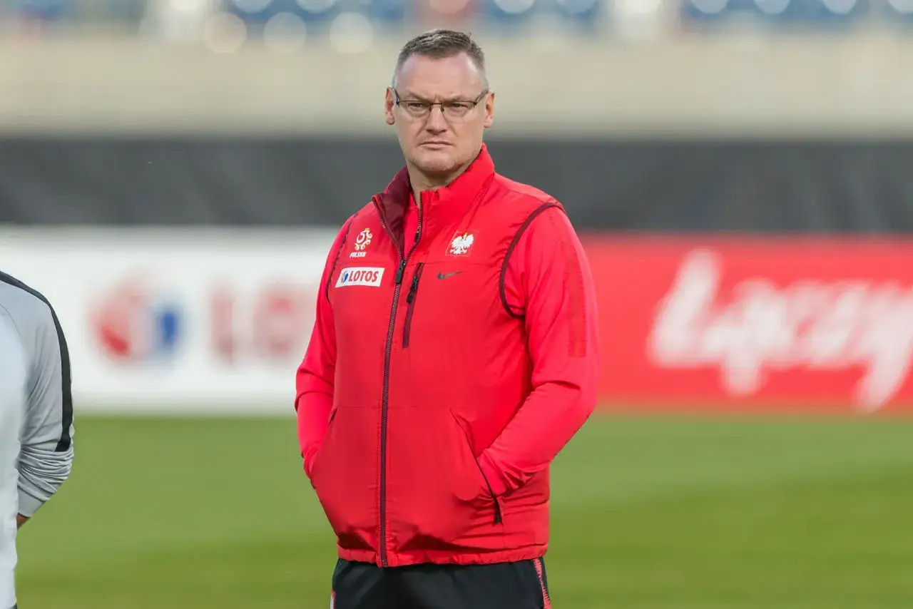 Miłosz Stępiński w czerwonej kamizelce z orłem na piersi, na tle boiska.