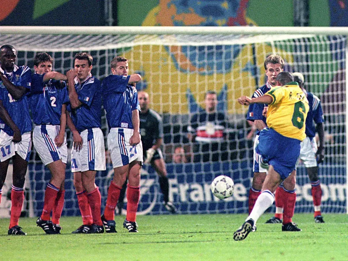 Brasiliens Roberto Carlos schie&szlig;t den Ball mit unglaublicher roberto carlos schuss geschwindigkeit auf das Tor. Franz&ouml;sische Spieler bilden eine Mauer.
