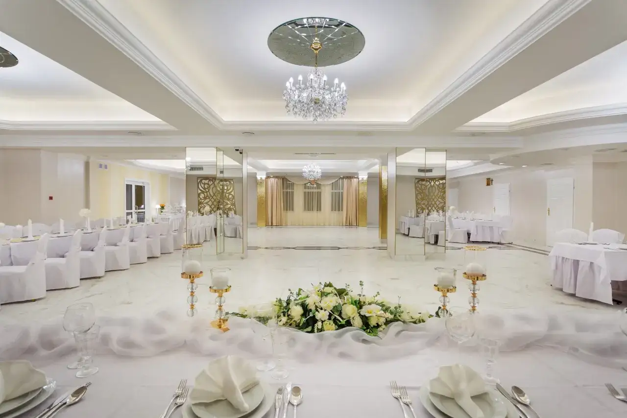 Elegancka sala bankietowa hotelu Santana Białystok, udekorowana białymi obrusami, świecami i kwiatami, gotowa na przyjęcie gości.