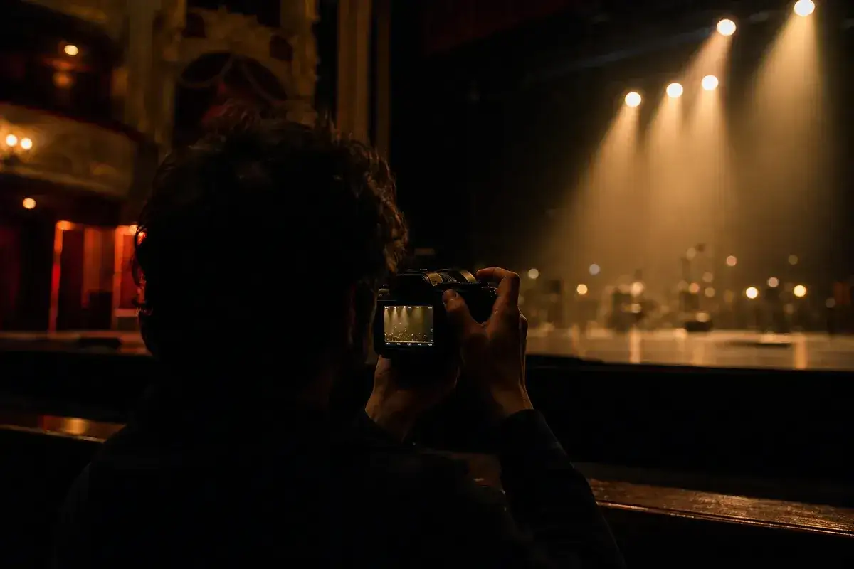 Un photographe ajuste son appareil pour un réglage photo concert, capturant la scène éclairée par des projecteurs chauds.