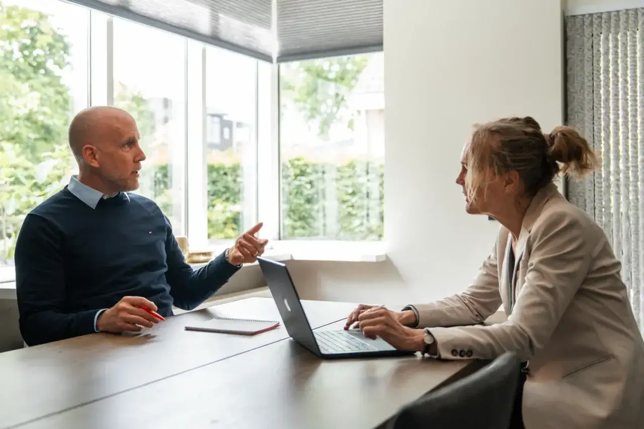 Man legt gesprekstechnieken voor lastige mensen uit aan vrouw met laptop.