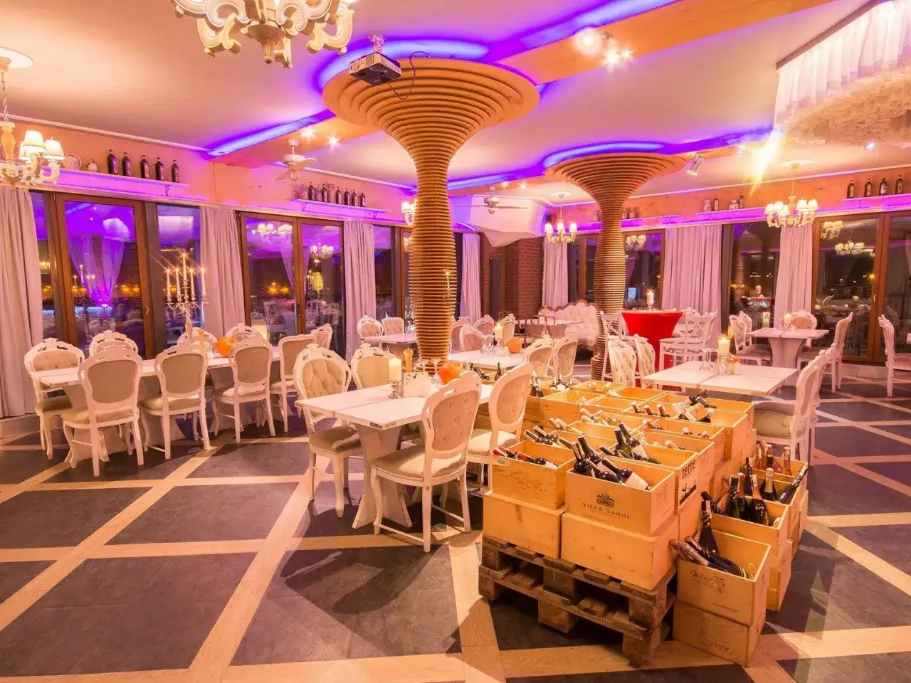 Elegancka sala bankietowa hotelu Ramka Poznań, oświetlona fioletowym światłem, z drewnianymi kolumnami i skrzynkami z winem.