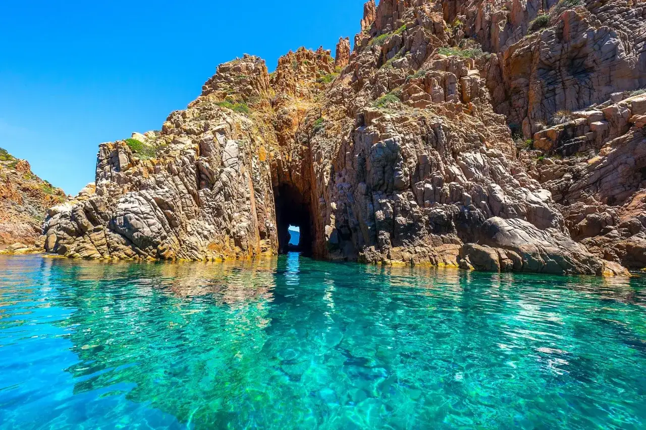 Eaux turquoise limpides menant à une arche rocheuse spectaculaire, un trésor caché de porto corse.