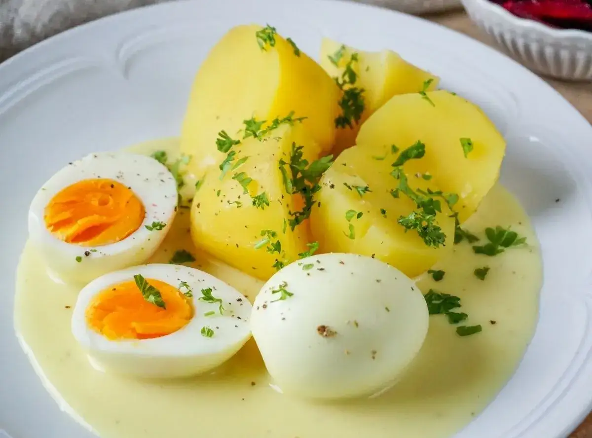 Gekochte Kartoffeln und halbe Eier in cremiger Senfsauce, garniert mit Petersilie. Ein Klassiker: Eier mit Senfsauce.