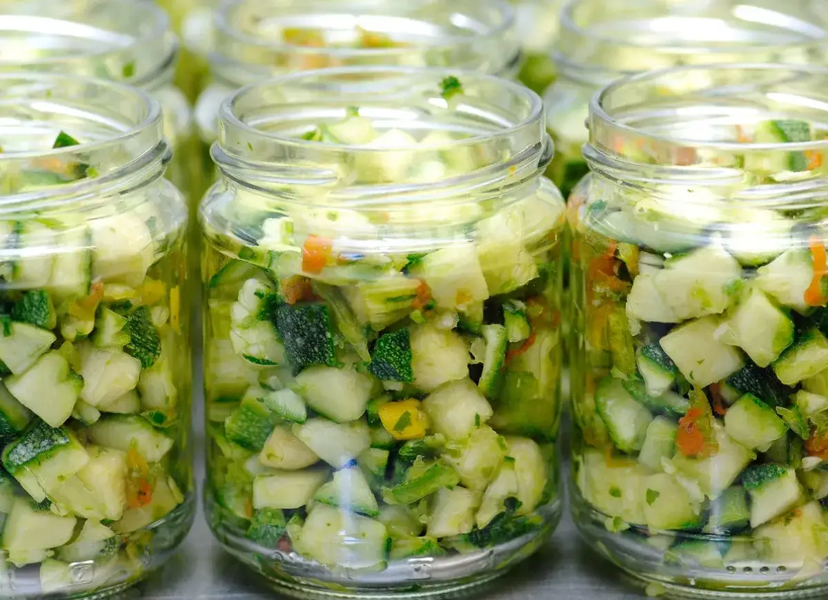 Słoiki z pokrojoną cukinią i innymi warzywami, wyglądające jak słodki ananas w zalewie.