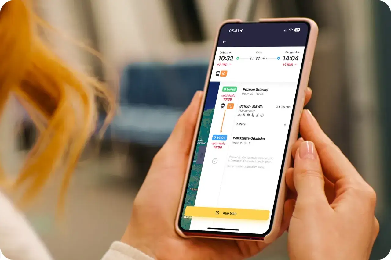 Kobieta przegląda w telefonie rozkład jazdy pociągów, szukając najlepszych intercity bilety. Widoczne są czasy odjazdów i przyjazdów.
