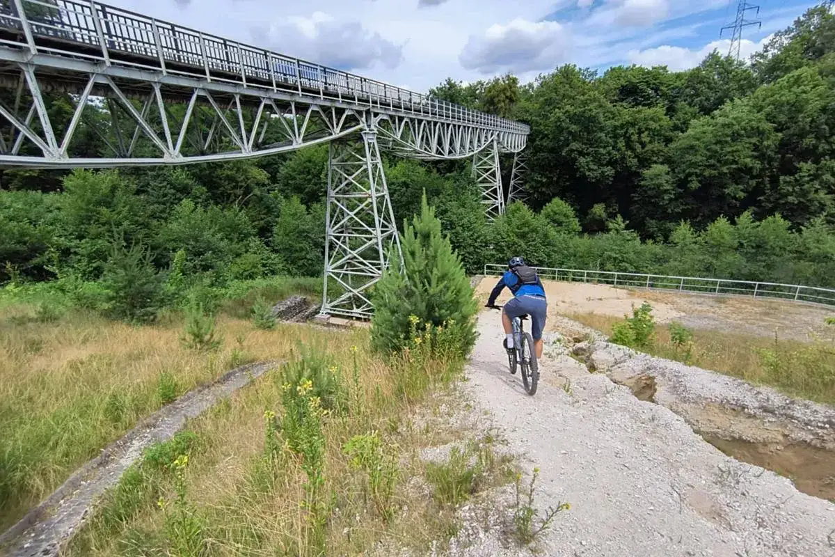 Rowerzysta na ścieżce pod wiaduktem kolejowym, odkrywa nowe trasy rowerowe Bydgoszcz.