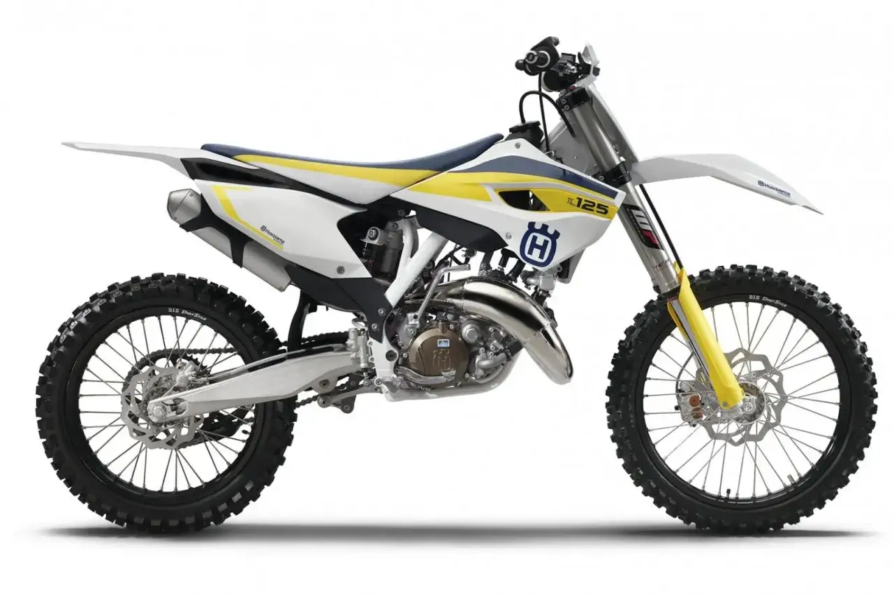 Husqvarna TE 125 gotowy do jazdy po torze. Biało-ż&oacute;łty motocykl crossowy z niebieskim siedzeniem.