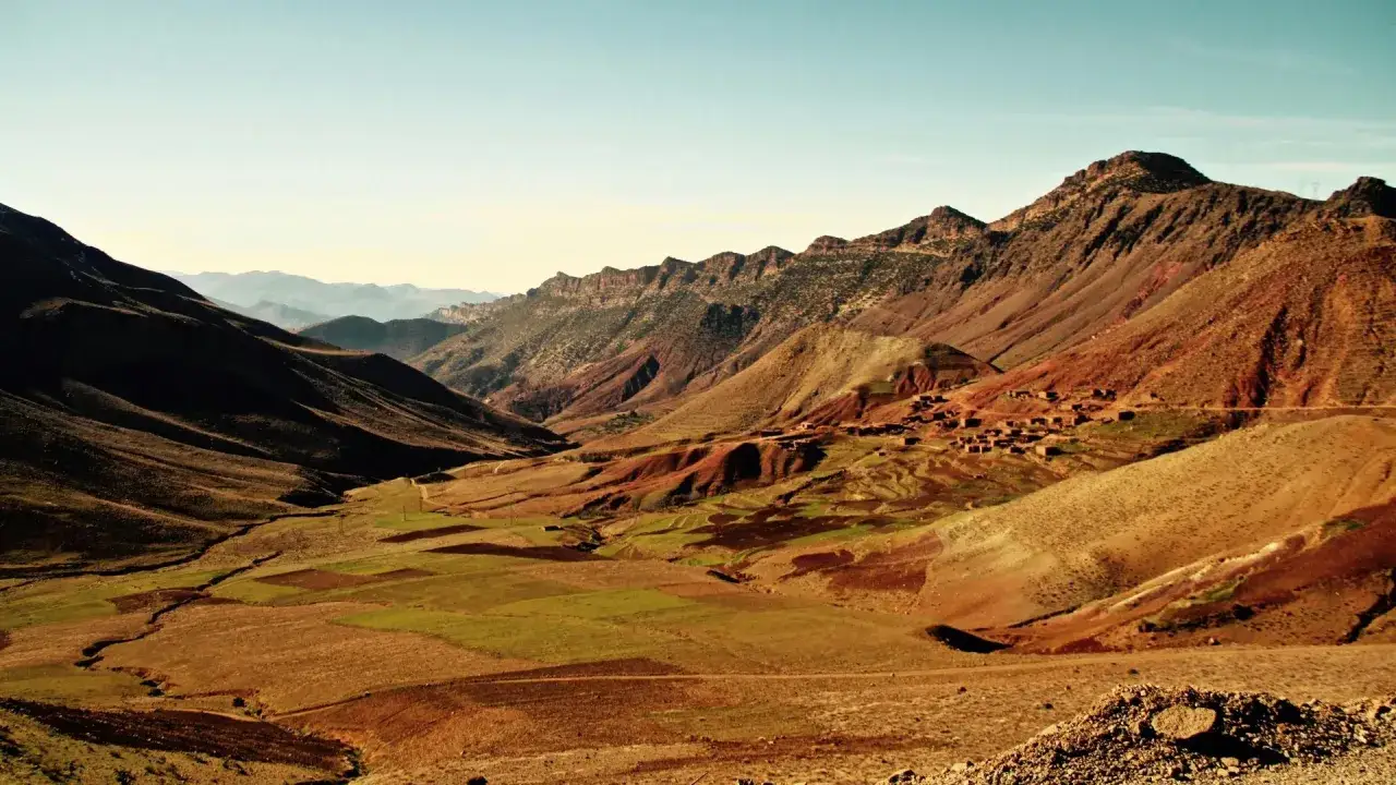 Malowniczy krajobraz gór Atlas w Afryce. Wąska dolina z polami uprawnymi i wioską na zboczu.