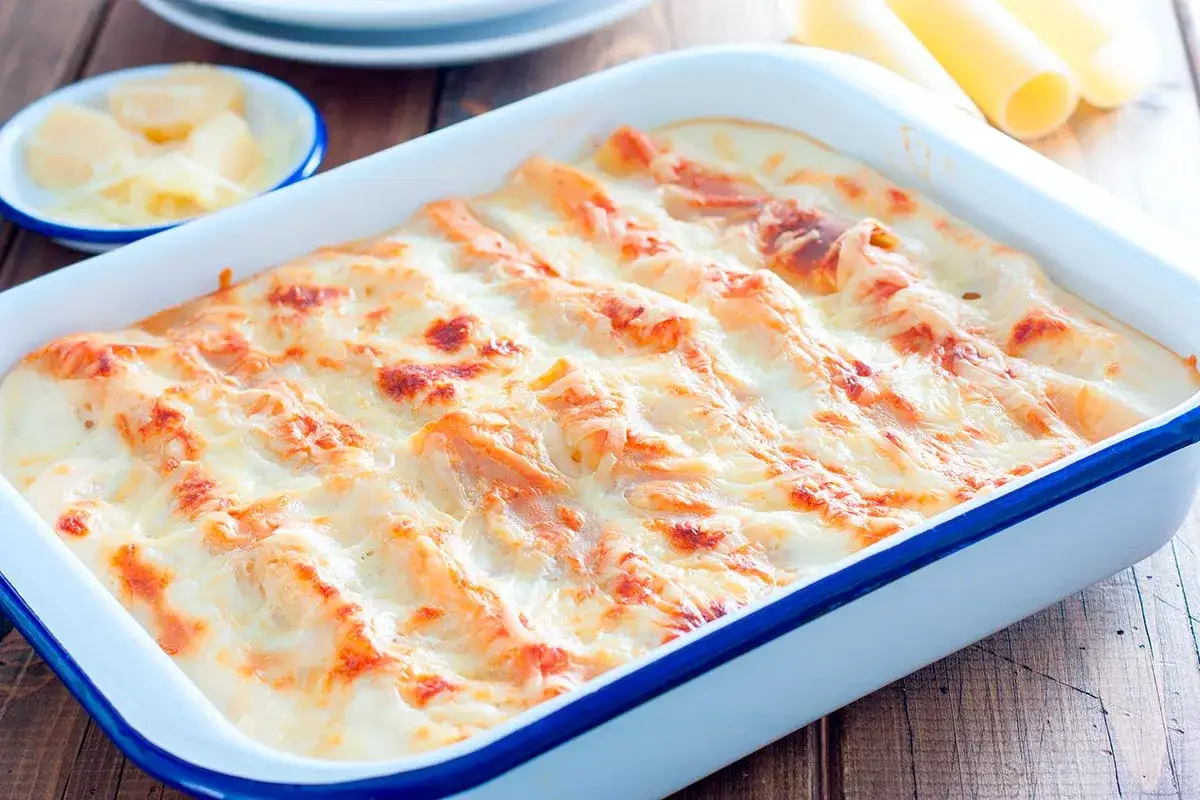 Canelones de carne recién horneados, cubiertos de queso derretido y dorado, listos para servir.