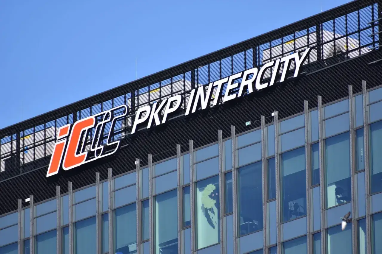 Logo PKP Intercity na nowoczesnym budynku. PKP to skrót od Polskich Kolei Państwowych, a Intercity to nazwa przewoźnika.