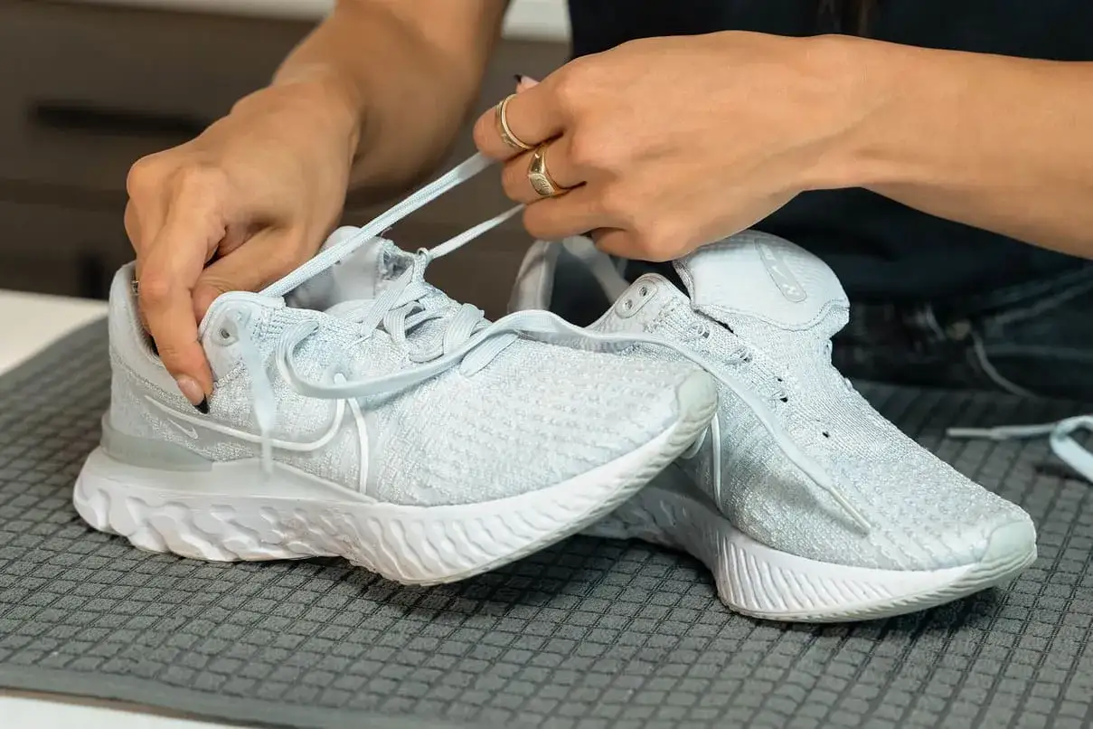 Hände binden hellblaue Nike Schuhe, bereit für die Waschmaschine.