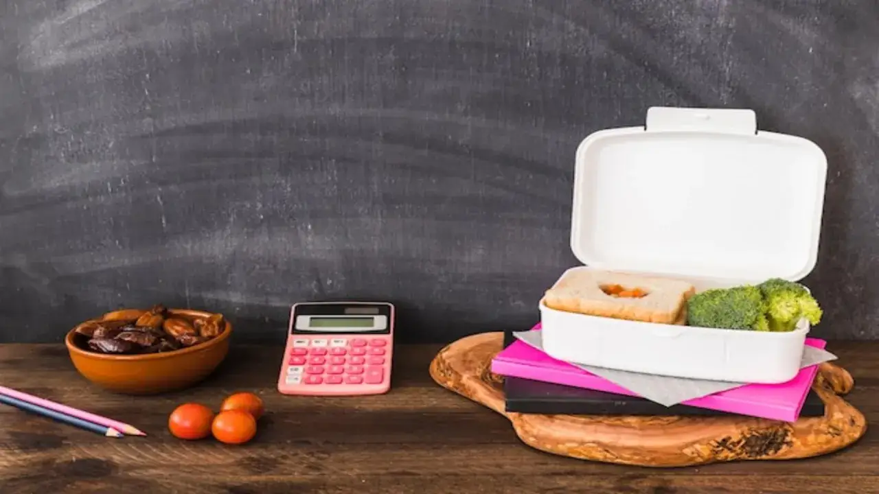 Kalkulator obok lunchboxa z kanapką i brokułami sugeruje, że warto policzyć, ile kosztuje dieta pudełkowa.