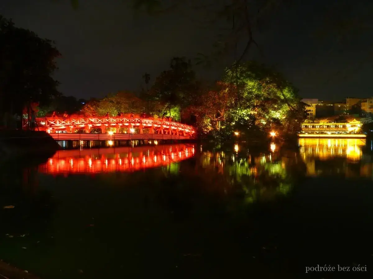 Czerwony most Huc Kiem i oświetlone drzewa nad jeziorem w Hanoi. To jedno z miejsc, które warto zobaczyć w stolicy Wietnamu.