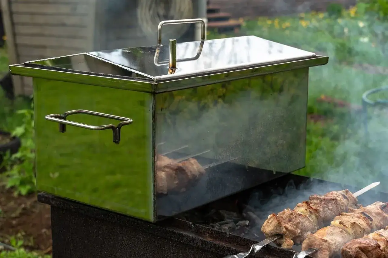 Wędzarnia na działce ROD. Mięso na szaszłykach dymi się, przygotowując się do grillowania.