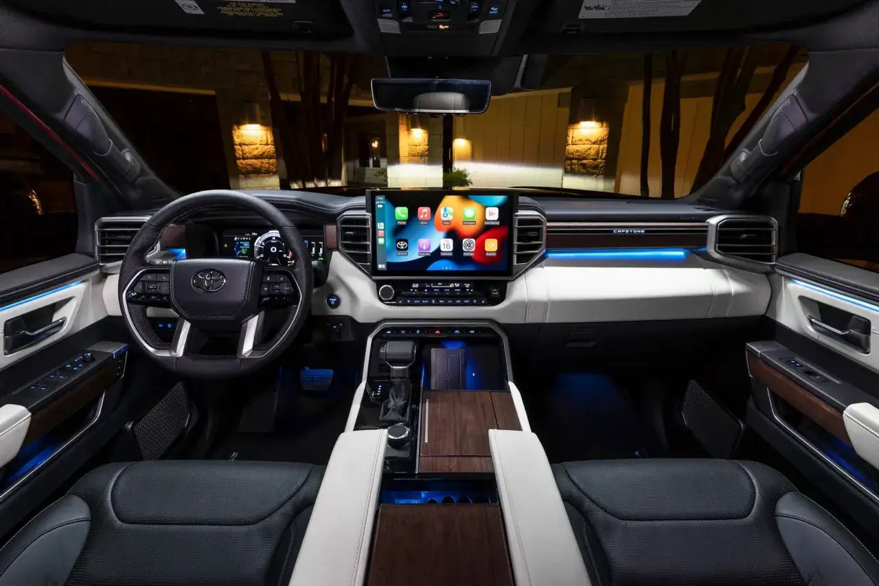 Wnętrze Toyota Sequoia Capstone: duży ekran multimedialny, skórzana kierownica, drewniane akcenty i nastrojowe oświetlenie tworzą luksusową atmosferę.
