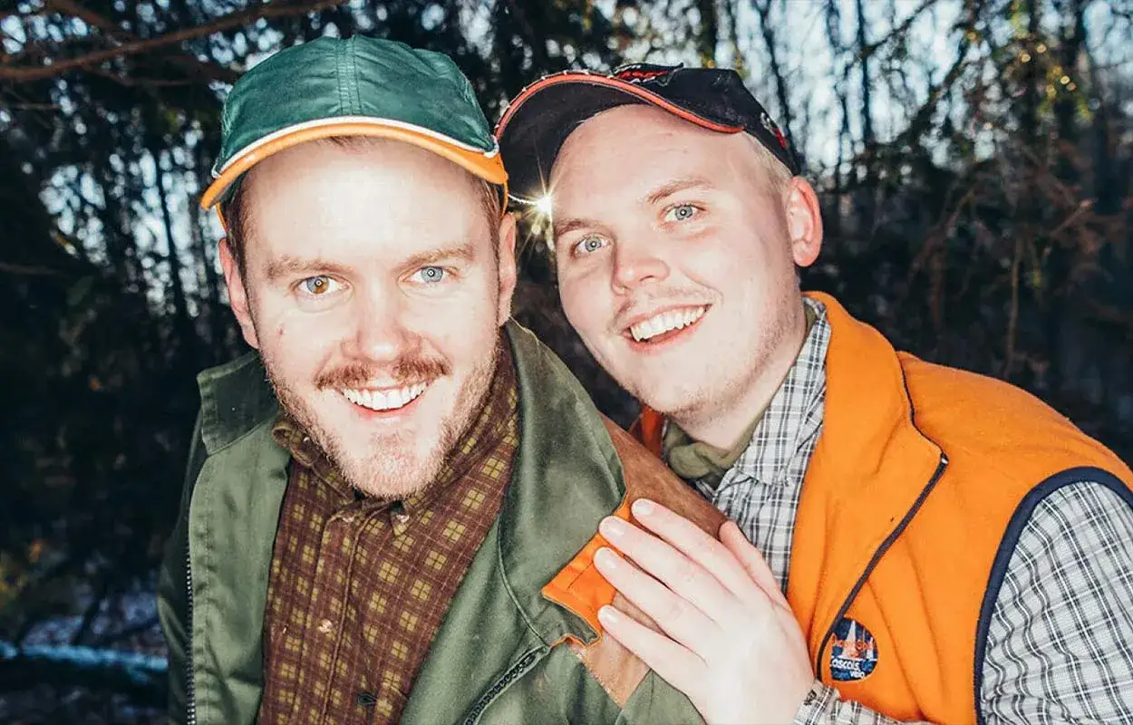 Två glada män, som från en leif och billy film, ler mot kameran utomhus.