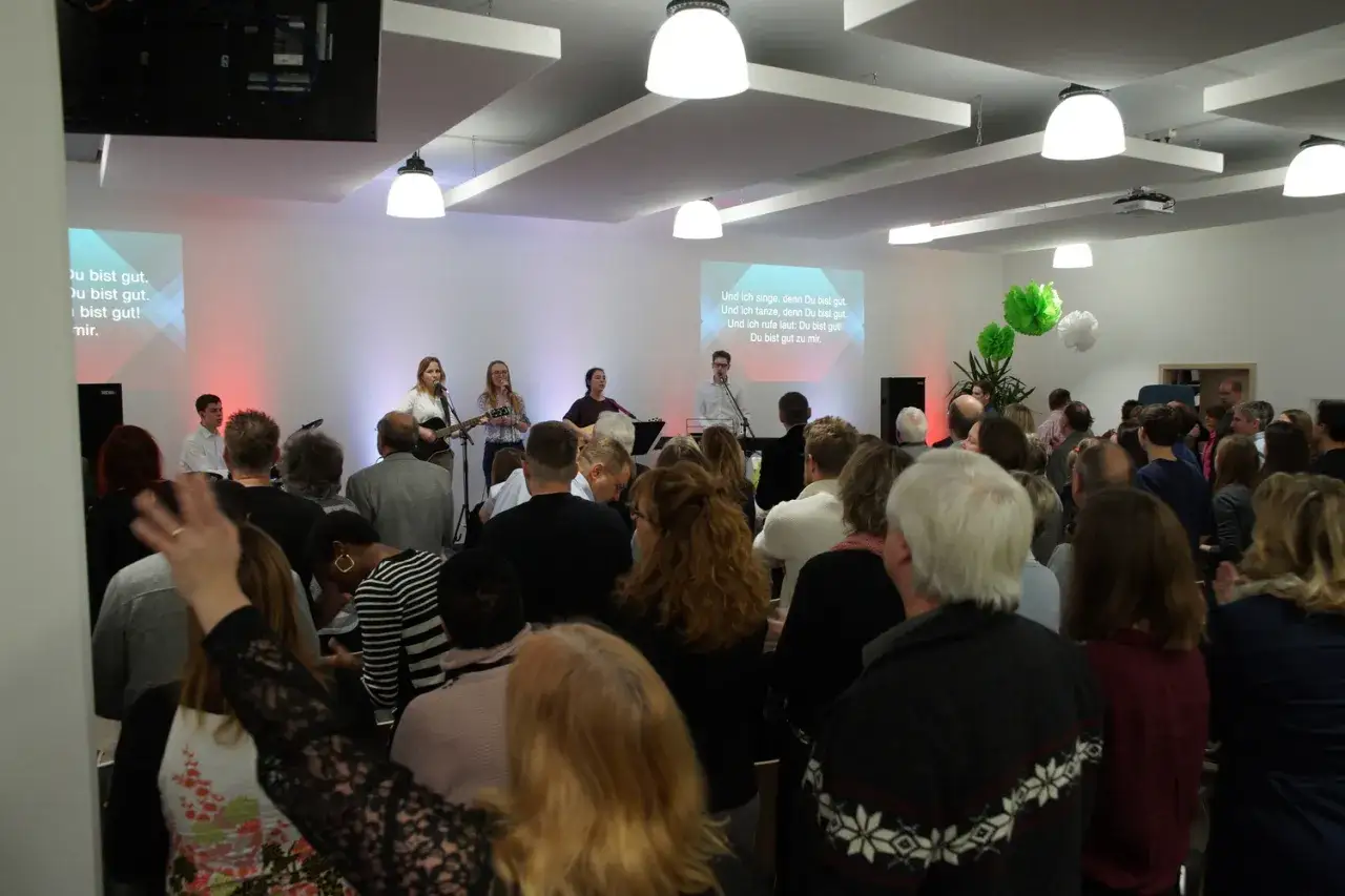 Gemeinde singt und tanzt zu Ehren Gottes, wie in Psalm 117 beschrieben. Texte auf der Leinwand preisen: 