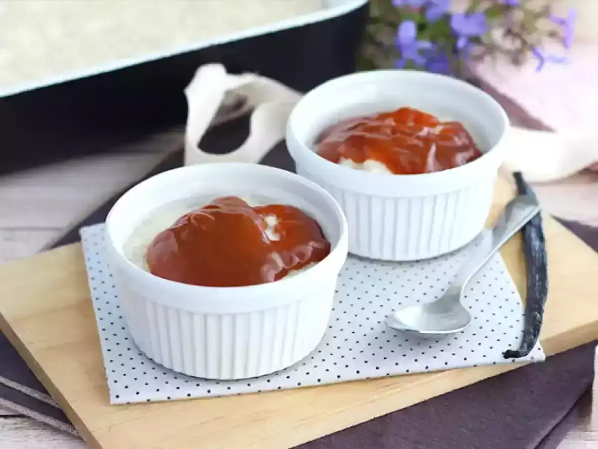 Zwei Schalen mit Omas Milchreis mit Butter und Kirschso&szlig;e, garniert mit einer Vanilleschote.