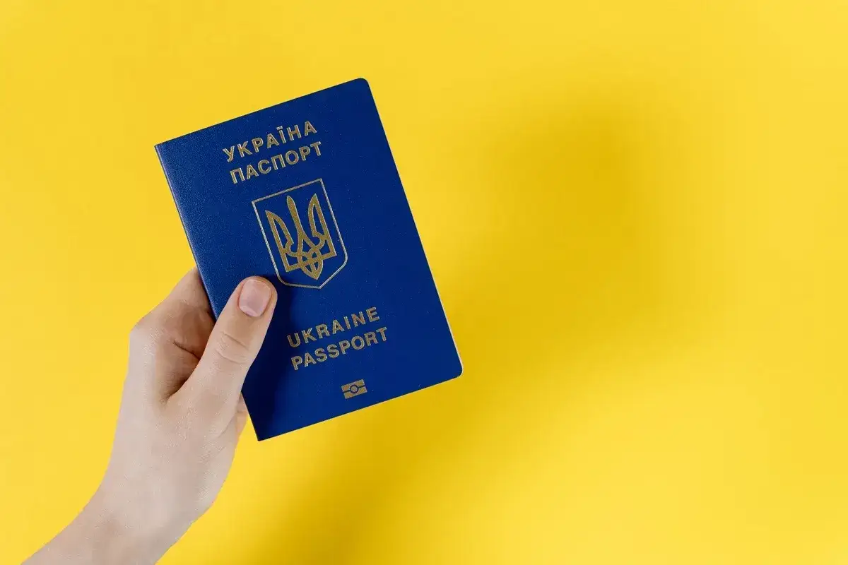 Dłoń trzyma niebieski paszport Ukrainy. Czy do Ukrainy potrzebny jest paszport? Tak, do podróży międzynarodowych.