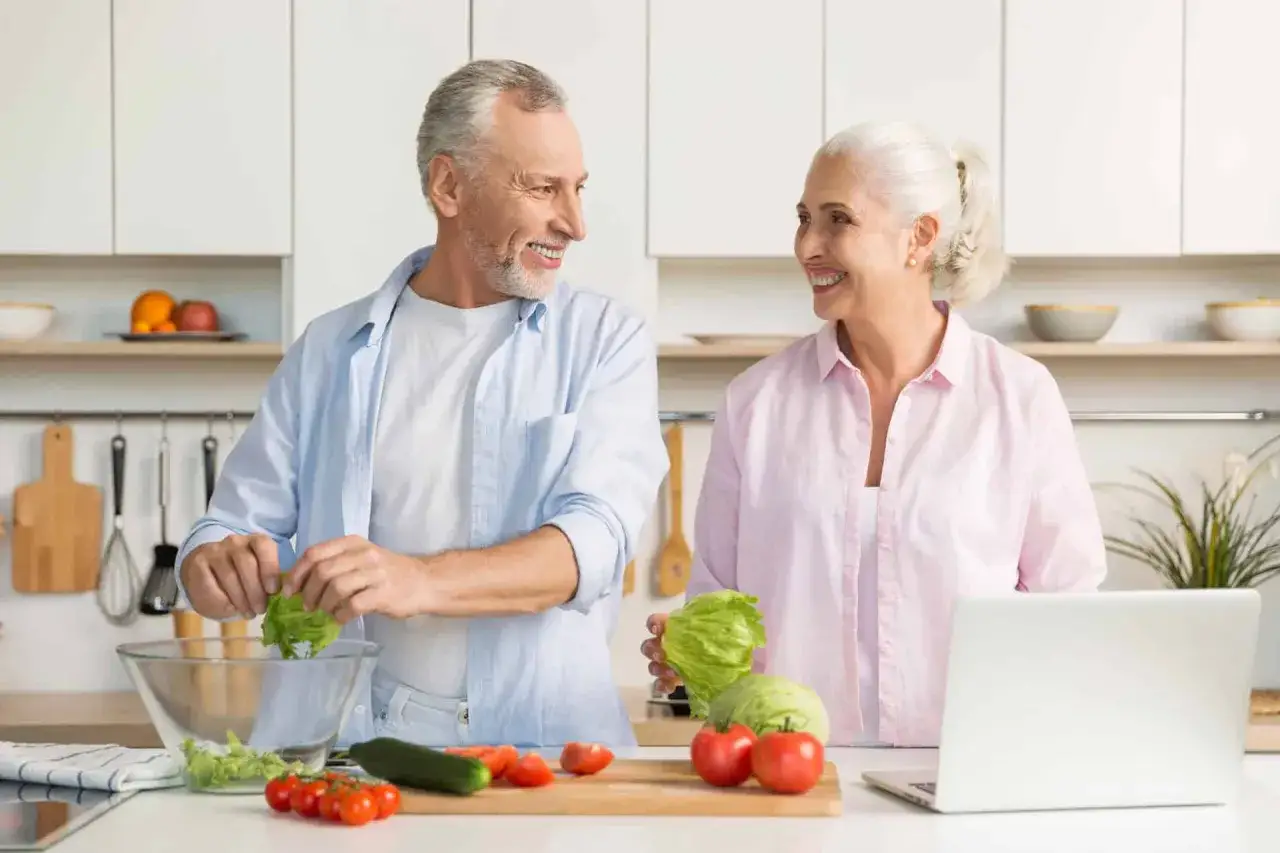 Szczęśliwa para seniorów przygotowuje zdrową sałatkę, inspirując się dietą dla par.