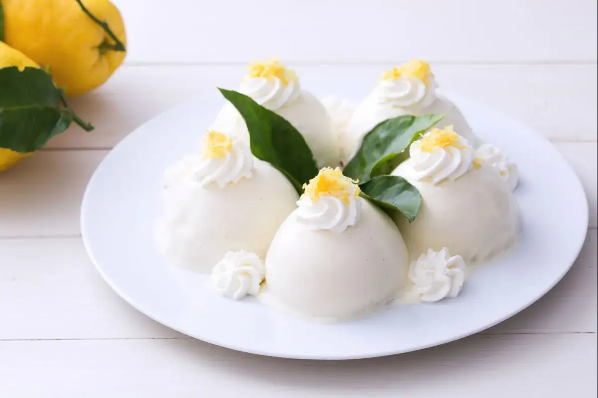 Sechs kleine, cremige Desserts, verziert mit Sahnetuffs und Zitronenschale. Diese köstliche crema pasticcera duftet nach Zitrone.