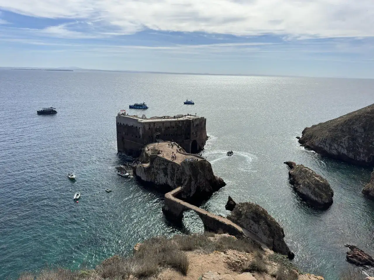 Festung auf den Berlengas Inseln, umgeben von t&uuml;rkisfarbenem Wasser, mit Booten und einer steinernen Br&uuml;cke.