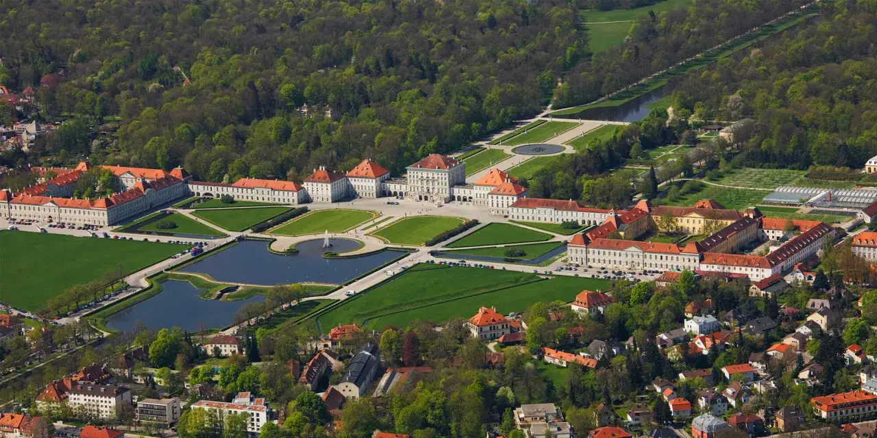 Luftaufnahme des Schlosses Nymphenburg, einer pr&auml;chtigen **Burg Bayerns**, mit weitl&auml;ufigen G&auml;rten, Seen und umliegenden Geb&auml;uden.