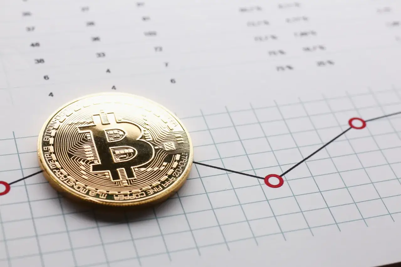 Złoty bitcoin na wykresie wzrostowym symbolizuje inwestowanie małych kwot w kryptowaluty.