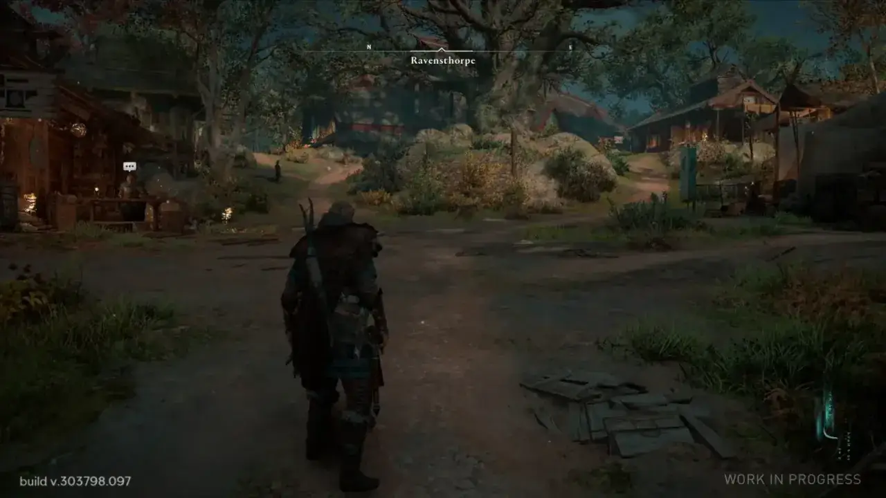 Wioska Ravensthorpe z gry Assassin's Creed Valhalla. Postać w zbroi stoi na drodze, otoczona drewnianymi budynkami i zielenią.