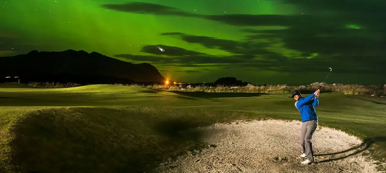 En golfare slår ett slag under norrskenet. En unik upplevelse av norsk golf.