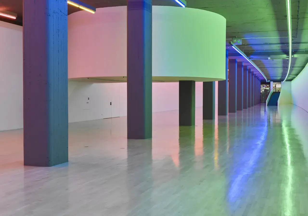 Beleuchtete S&auml;ulen und runde Installationen im Kunstbau Lenbachhaus. Der Boden reflektiert das bunte Licht.
