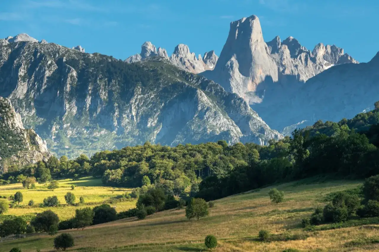 Grüne Hügel und Wälder vor majestätischen Bergen. Perfekt für **Asturien wandern** und die Natur genießen.