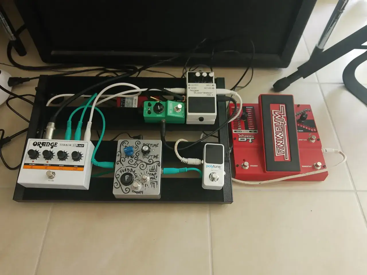 Ein Pedalboard mit einem weißen Orange Terror Stamp, einem grünen Tube Screamer, einem silbernen Feedback-Pedal und einem roten Whammy DT.