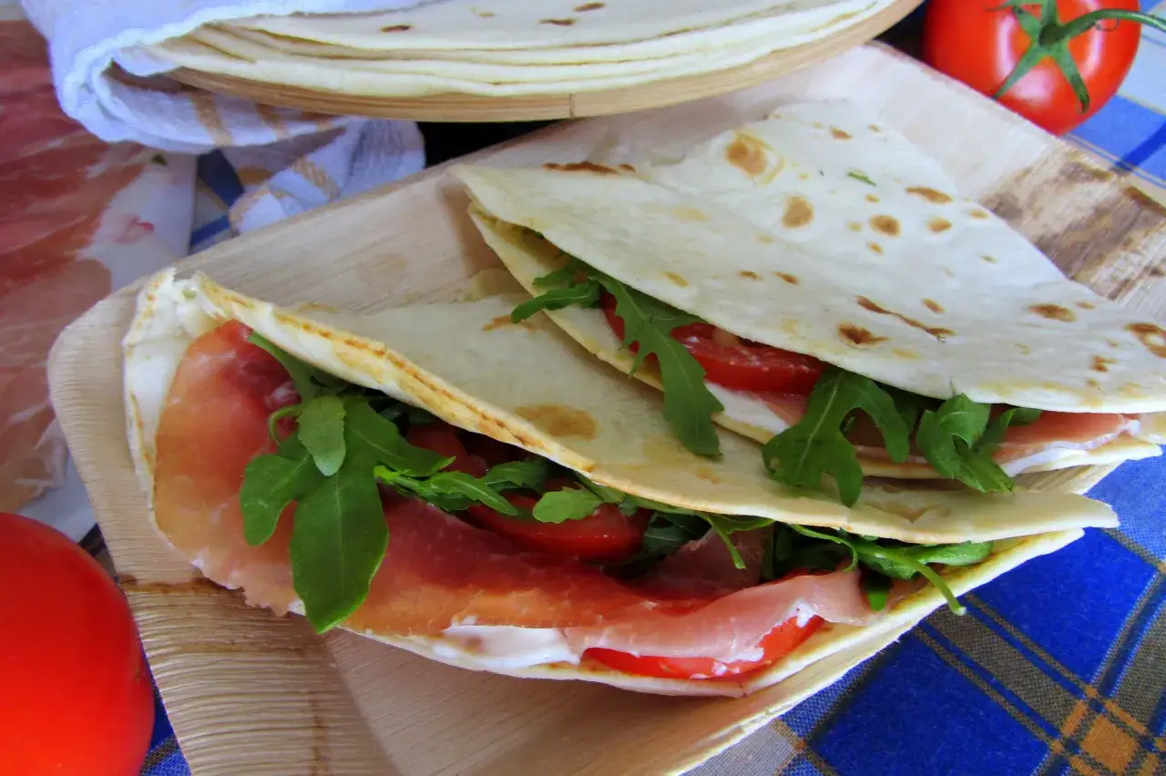 Pyszna piadina z szynką parmeńską, rukolą i pomidorami, gotowa do zjedzenia.