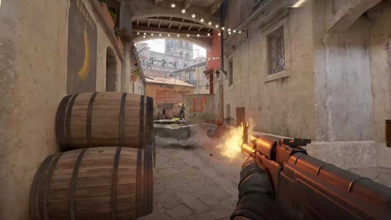 Gracz celuje z karabinu, widoczne celowniki CS GO. W tle beczki i wąska uliczka z budynkami.