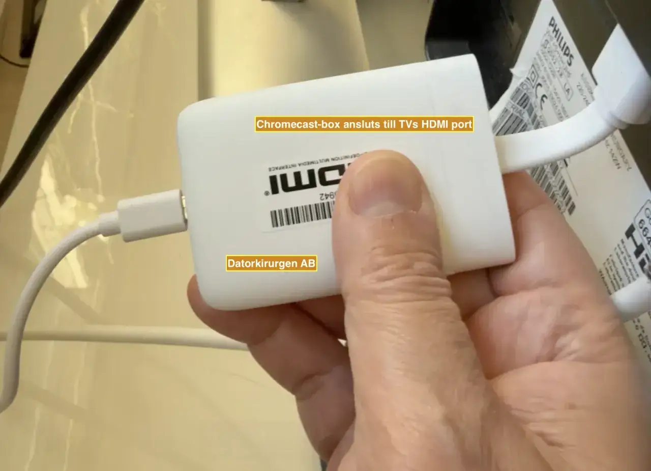 En hand h&aring;ller en vit Chromecast-box ansluten till en TV, redo f&ouml;r iptv Tele2.