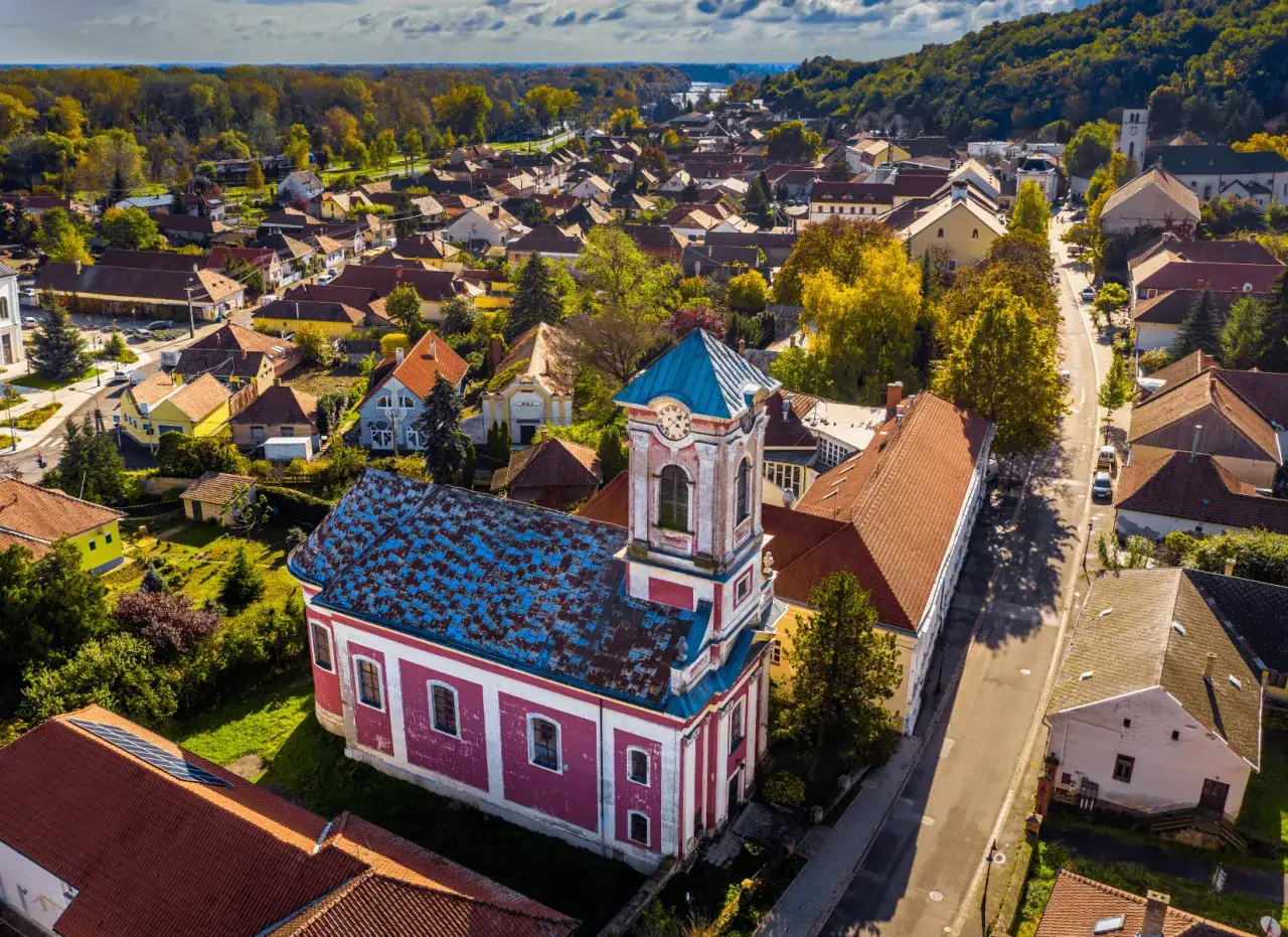 Urokliwy kości&oacute;ł z niebieskim dachem i r&oacute;żową fasadą w malowniczej wiosce na Węgrzech. Węgry najpiękniejsze miejsca.