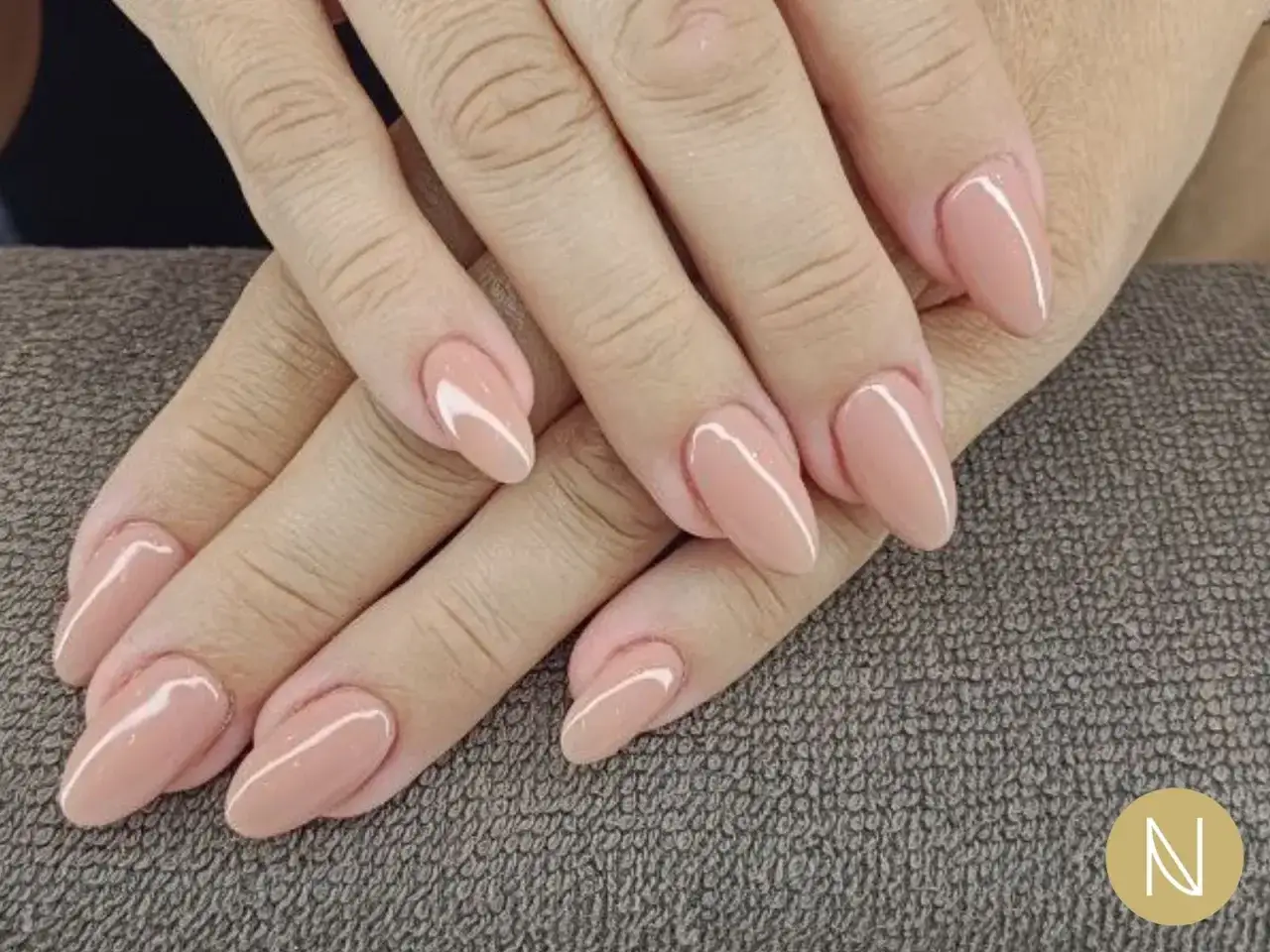 Mani curate con unghie french eleganti, color nude e forma a mandorla, perfette per ogni occasione.